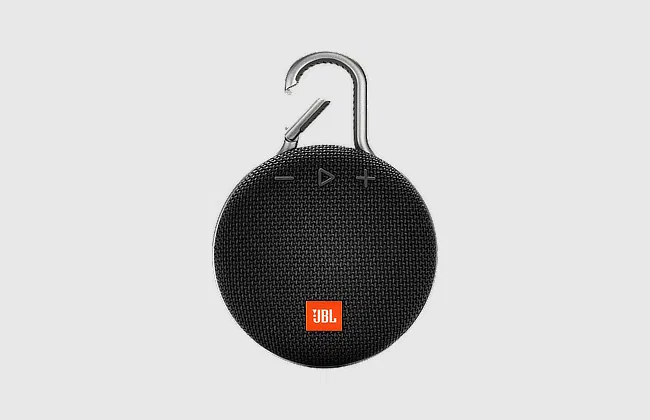 Front view of a black, round JBL Bluetooth speaker with top carabiner, textured front, 3 controls, and logo at the bottom.