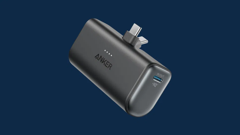 Front view of a black Anker portable charger with USB-C port, LED indicators, and integrated plugs on a dark blue background.