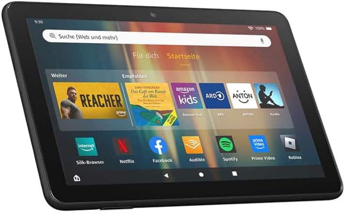 Black tablet shown in angled front view, display on with app icons like Netflix, Prime Video, Amazon Kids, and Audible visible.