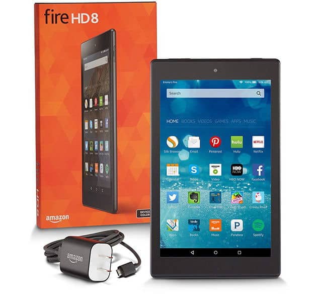 Front view of Amazon Fire HD 8 tablet with screen on, orange retail box behind, and charging cable with plug in foreground.