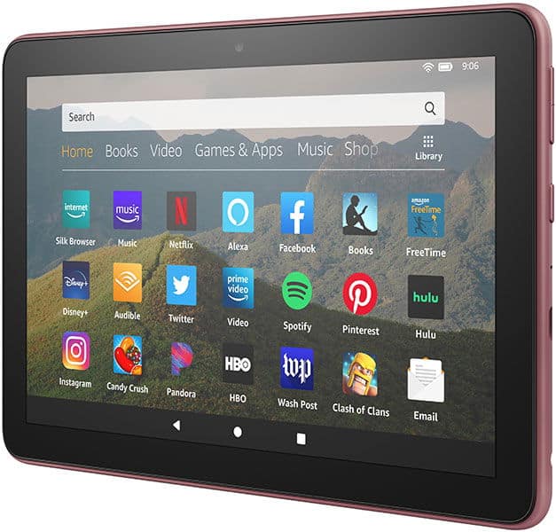 Front view of a pink Amazon Fire tablet showing home screen with popular app icons on a mountain landscape background.