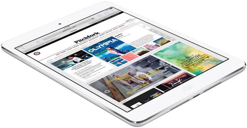 Apple iPad (white) front angled view showing the Pitchfork website homepage, on a white background.