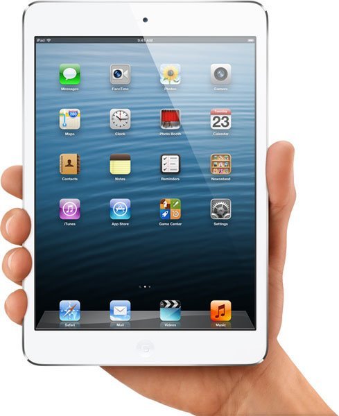 Front view of a white Apple iPad Mini held in hand, showing home screen with app icons on a blue wave background.