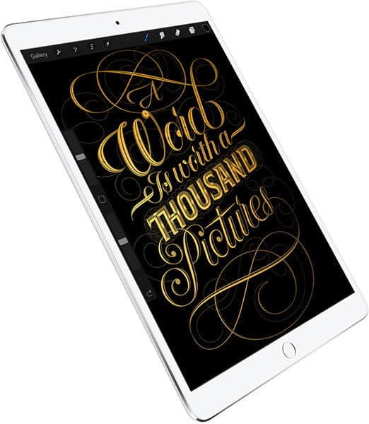 Tablet shown at an angle with digital artwork on screen reading "A word is worth a thousand pictures" in gold on black.