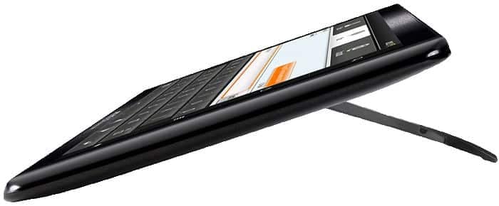 Side view of a black wireless keyboard with rear stand extended, supporting a tablet showing an on-screen keyboard and chat.