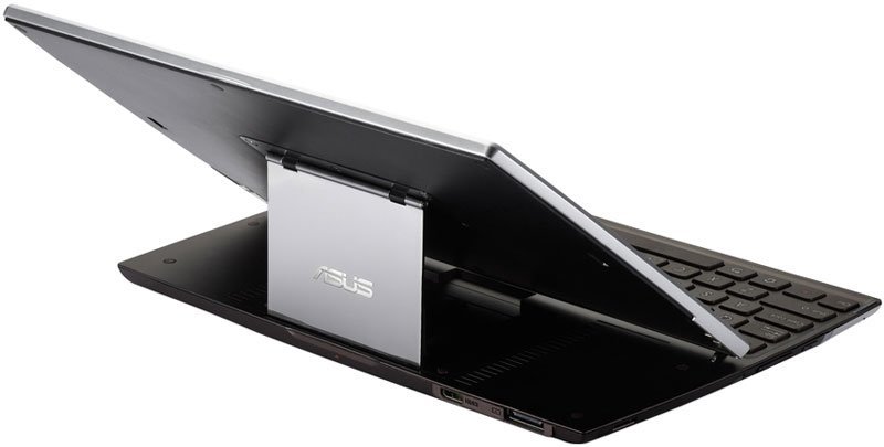 Asus Transformer silver tablet partially detached from black keyboard, side view showing hinge, ports, and rear Asus logo.