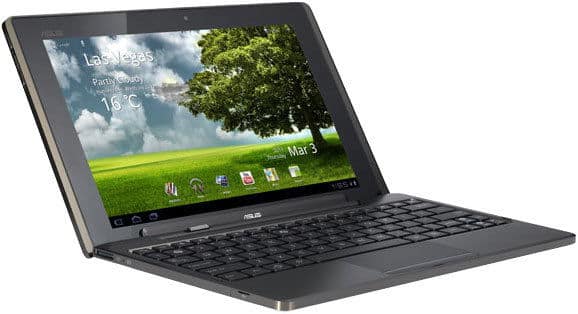 Front view of black Asus tablet with detachable keyboard, open on white surface. Screen displays Las Vegas weather and app icons.