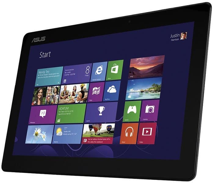 Front view of a black Asus tablet showing Windows 8 Start screen with app tiles; user “Justin Hamilton” in top right.