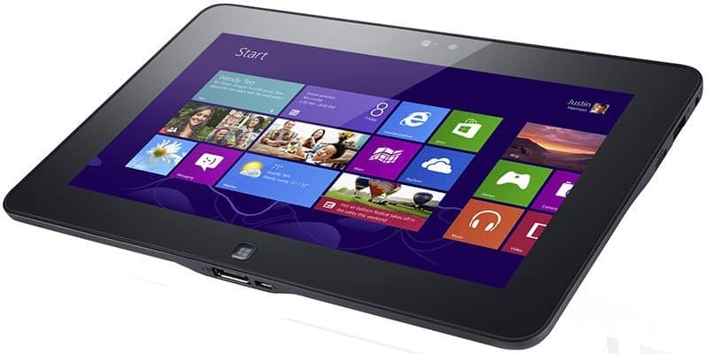Black tablet, angled front view, shows Windows 8 start screen with colorful app tiles on a white background.