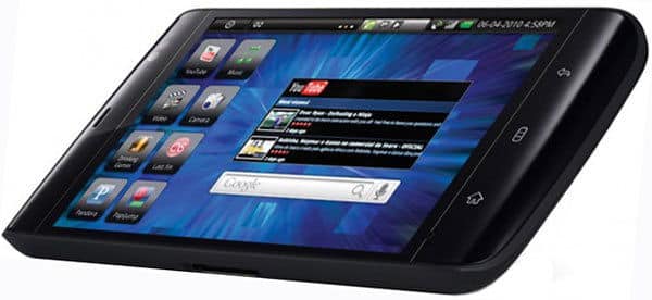 Black touchscreen tablet, possibly Samsung Galaxy Tab, angled front view, blue geometric wallpaper, app icons, YouTube video shown.
