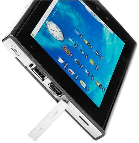 Angled front view of a black tablet (brand/model unspecified) with blue app screen, clock widget, and white USB device connected.