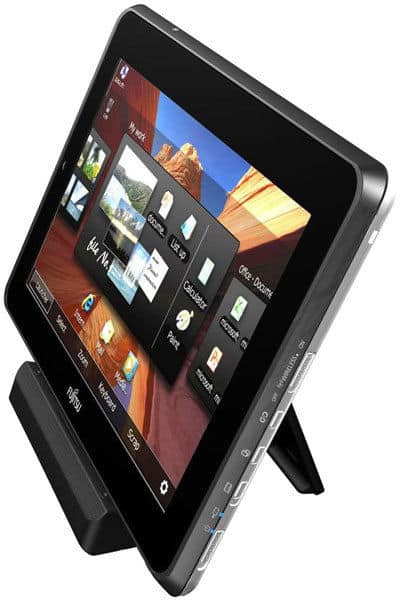 Black tablet (brand/model unspecified) on a stand, angled right, showing home screen with app icons and scenic wallpaper.