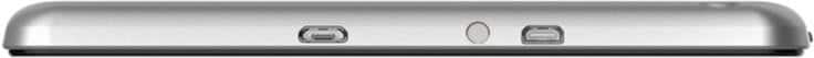 Close-up side view of a silver tablet's flat edge with two small ports and a circular button or indicator between them. Brand unknown.