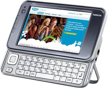 Front view of Nokia N97 showing slide-out QWERTY keyboard, touchscreen open to Skype site, propped up with built-in stand.