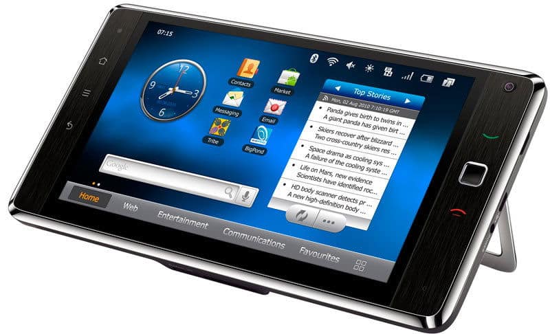 Black smartphone, likely Samsung Galaxy, angled front view with clock, apps, news on screen; propped by built-in stand.