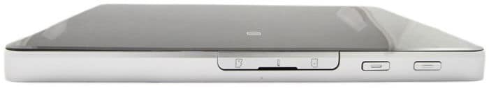 Side close-up of a slim silver tablet with glossy black top, SIM card slot, and two buttons. Brand/model not specified.