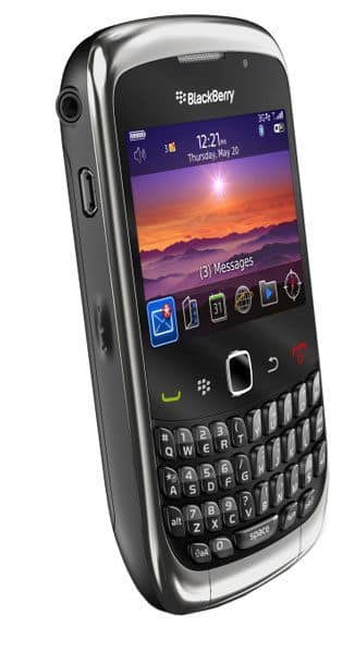 BlackBerry 9330 front view, displaying sunset wallpaper on screen with QWERTY keyboard below