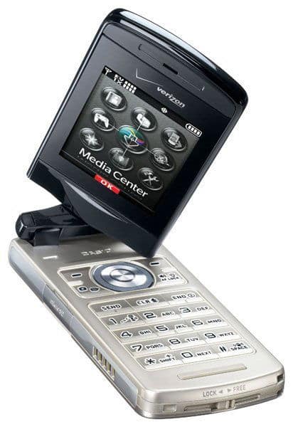 Casio EXILIM flip phone, open, showing silver lower half with keypad and blue navigation dial, and dark upper screen displaying Media Center menu