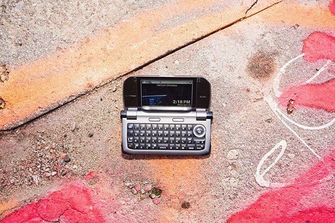 Casio Brigade G'zOne front view, open with slide-out keyboard displayed on weathered pavement with pink paint markings