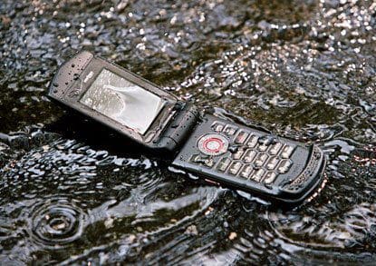 Casio GzOne Ravine open in water, showing front screen and keypad with flip design submerged in rippling water