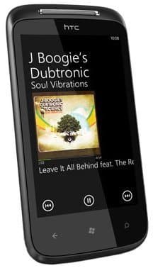 Front view of black HTC 7 Mozart showing music player screen with "Soul Vibrations" album and track details visible.