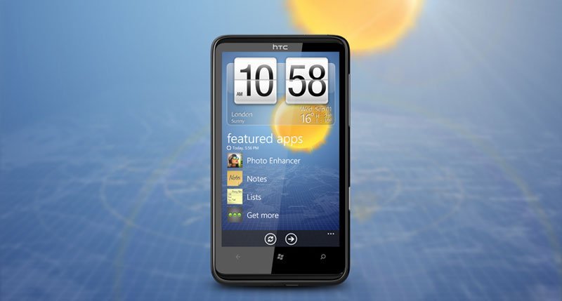HTC HD7 front view displaying home screen with time 10:58, weather widget for London, and featured apps including Photo Enhancer, Notes, and Lists