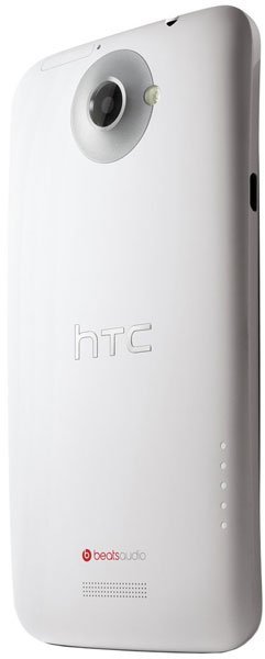 Rear view of white HTC One X showing camera with flash, HTC and Beats Audio logos, speaker grille, and lower side dots.