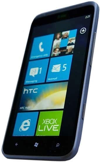 HTC Titan II front view, displaying Windows Phone interface with blue tiles for contacts, messages, photos, and Xbox Live
