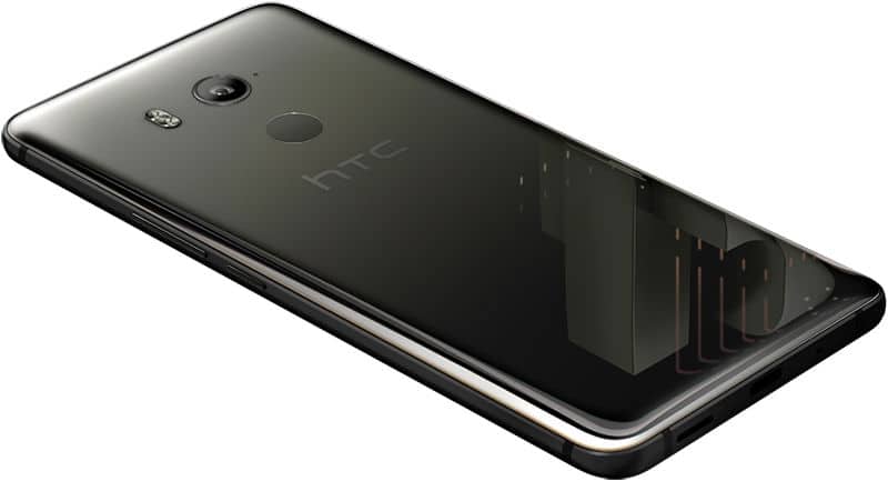 HTC U11+ (black) rear view at angle, showing camera, fingerprint sensor, and reflective glass back with HTC logo.