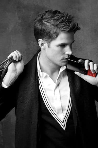 Man in black blazer and white shirt holding LG New Chocolate BL20 phone to his ear, side profile against gray background