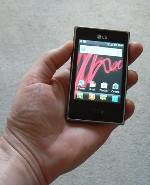 LG Optimus L3 smartphone held in hand, front view with screen on displaying home screen and app icons