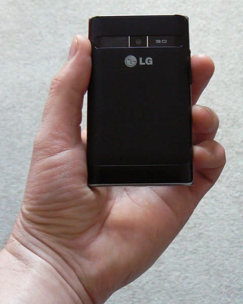 LG Optimus L3 smartphone held in hand, front view, black screen showing LG logo and status icons