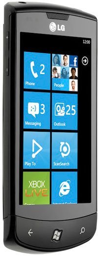 Front view of black LG Optimus 7 showing Windows Phone home screen with blue tiles at 12:00. Apps: Phone, People, Xbox Live.