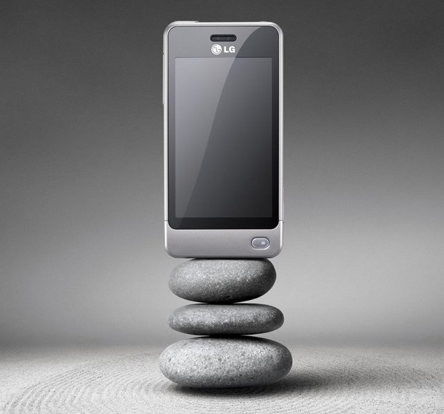 Front view of a silver LG Pop touchscreen phone upright on four gray stones, against a textured surface and gradient gray background.