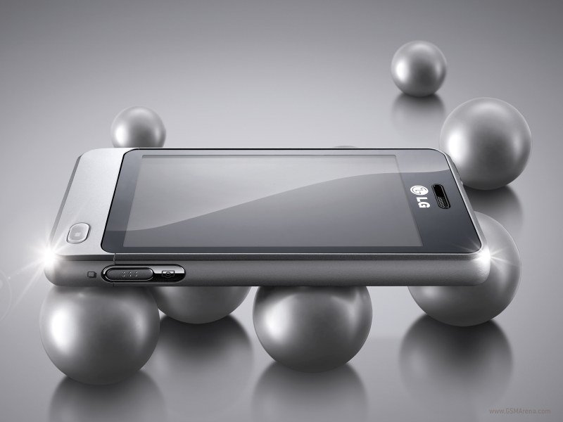 Silver LG Pop smartphone shown in horizontal side view, screen off, side buttons visible, on silver spheres with a gray backdrop.