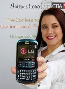 Woman displays front view of LG Remarq with physical keyboard; conference signage visible in background.