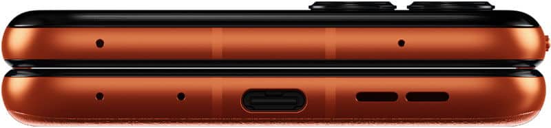 Side view close-up of orange Motorola Razr 50 hinge with USB-C port, speaker grill, mic holes, and precisely aligned halves.