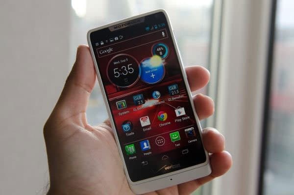Motorola DROID RAZR M front view, held in hand, displaying home screen with widgets and app icons, white phone with dark screen