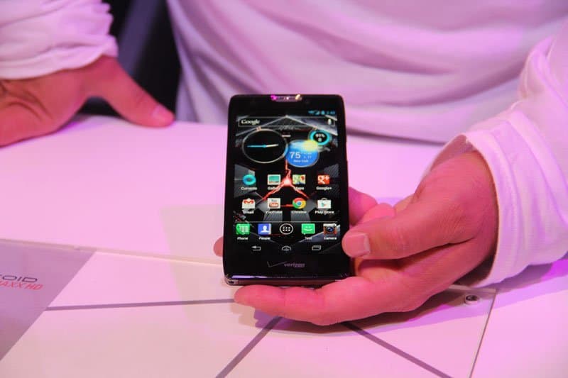 Front view of Motorola DROID RAZR HD Verizon held in hand, displaying various apps on screen above a white surface.