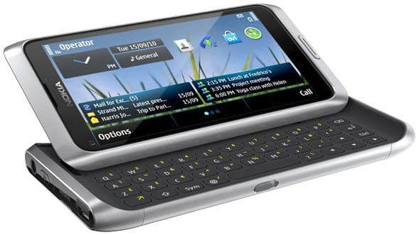 Nokia E7 front view, slide-out QWERTY keyboard partially open, home screen with app icons and digital clock visible.