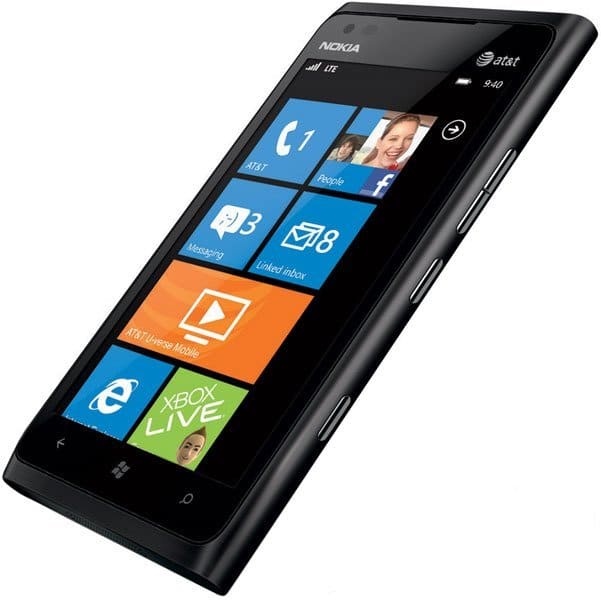 Nokia Lumia 900 front view, black smartphone with colorful Windows tiles on screen including contacts, calendar, and Xbox Live apps