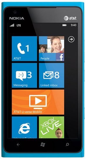 Nokia Lumia 900 front view with blue case, displaying Windows Phone home screen with app tiles for AT&T, People, Messaging, and Linked Inbox