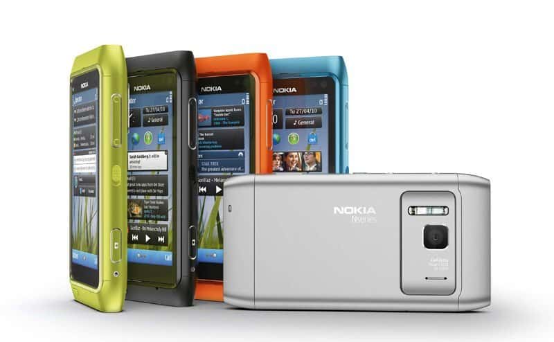 Nokia N8 phones in lime green, black, orange, and blue, displayed front and rear views showing touchscreen interfaces and camera lens