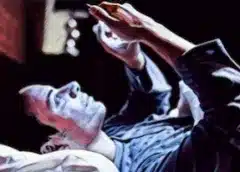 Person in bed at night holding a smartphone up, using a blue light filtering app for better sleep