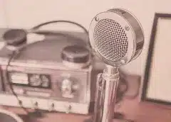 Vintage microphone and audio recorder on a desk, representing podcast recording setup