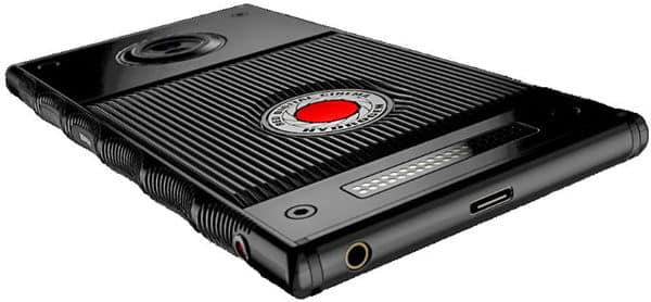 Angled rear close-up of Red Hydrogen One showing ridged back, RED logo, camera lens, headphone jack, charging port, and pins.