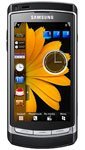 Front view of black Samsung Omnia HD showing large yellow flower wallpaper, digital clock, app icons, and widgets on touchscreen.