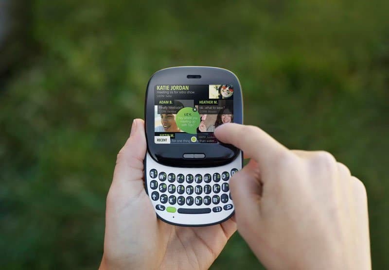 Sharp Kin One front view displaying social messaging interface with contacts and keyboard in hands against blurred green background