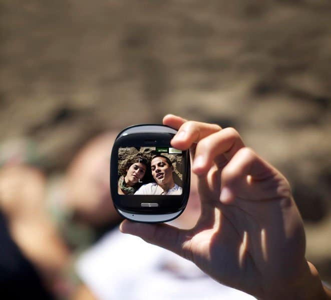 Sharp Kin One phone held up displaying two people on its small screen, with blurred background