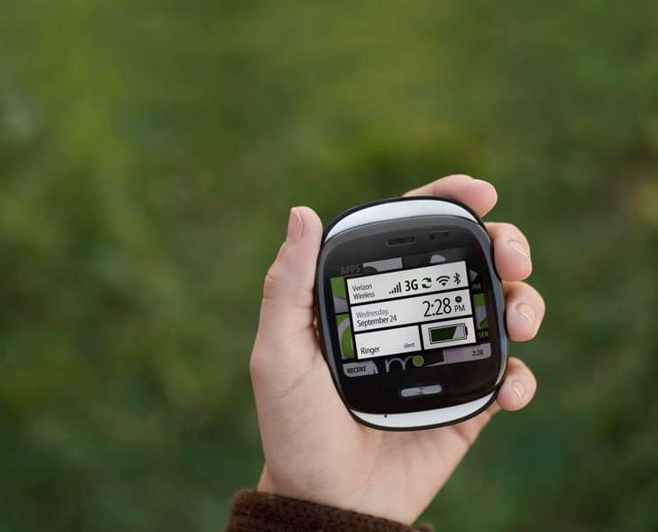 Sharp Kin One smartphone held in hand, displaying home screen with time, date, and status icons